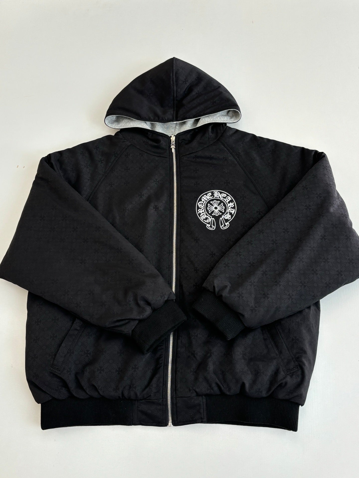 Black zip-up hoodie with hood and round chest emblem patch