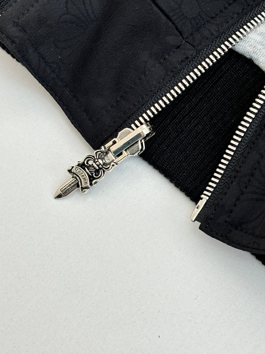 Black hoodie close-up of silver zipper pull and seam