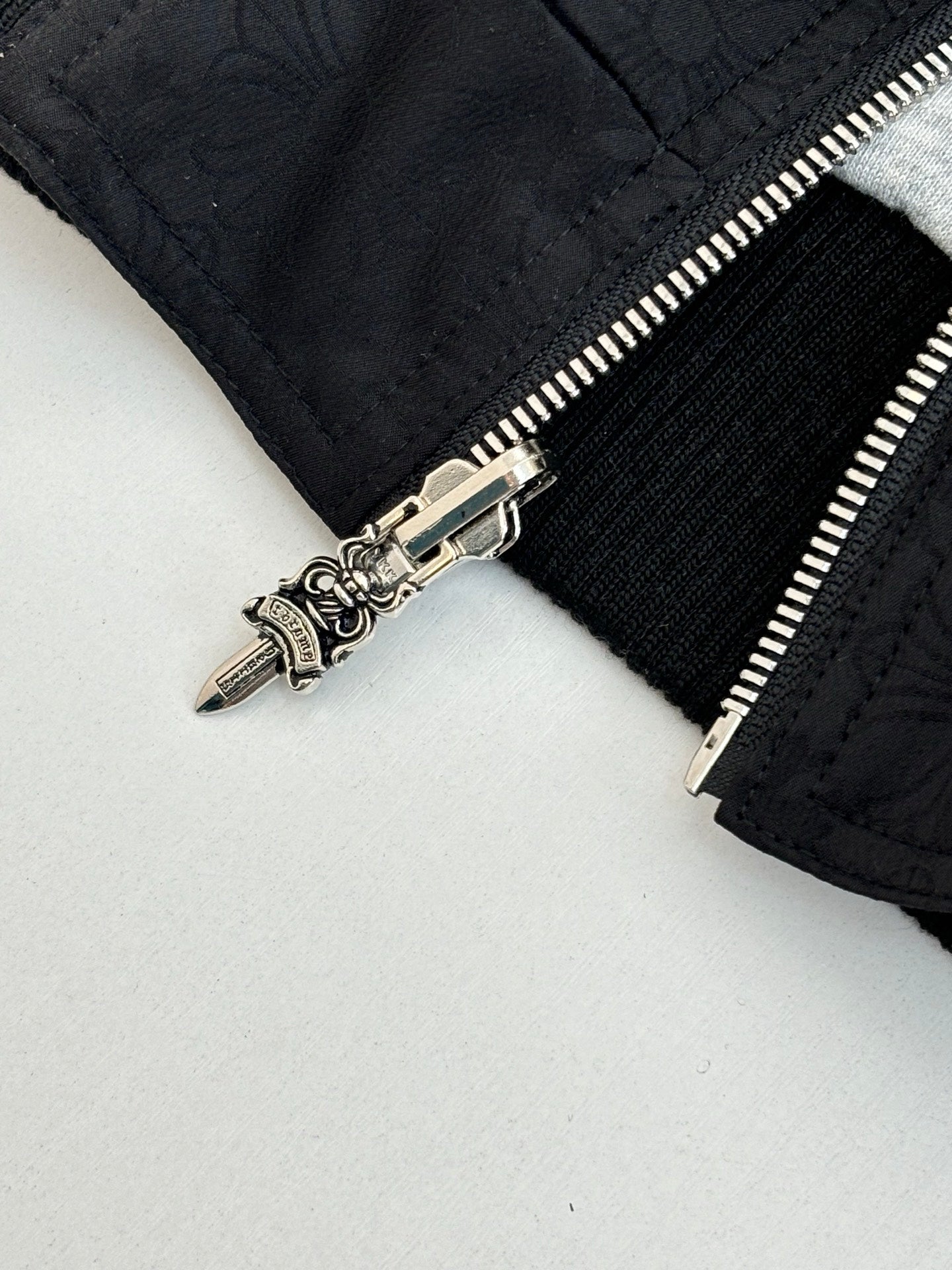 Black hoodie close-up of silver zipper pull and seam