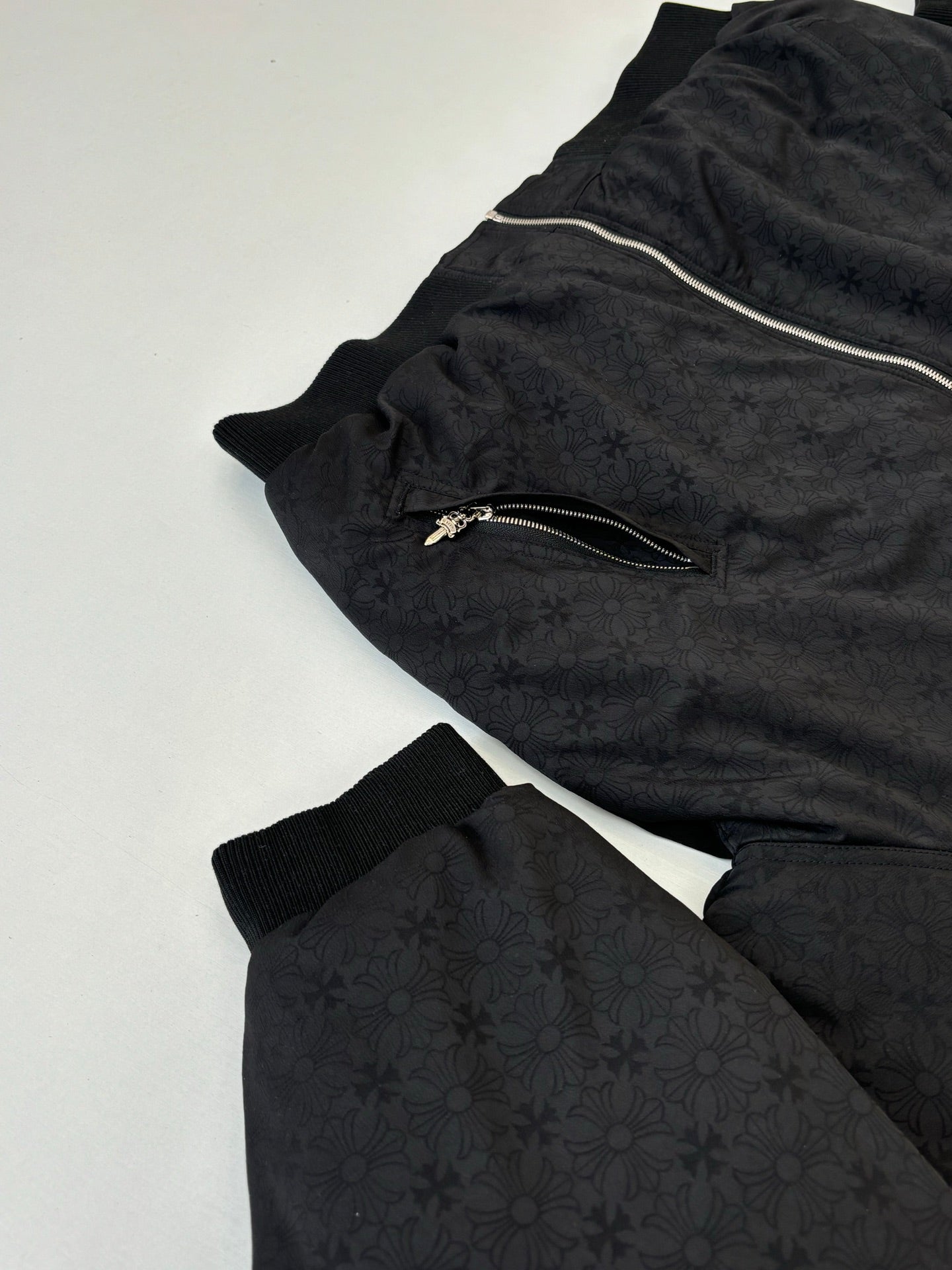 Black zip-up hoodie laid flat with hood, visible zipper, and textured pattern
