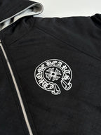 Black zip-up hoodie with hood and white circular chest logo on textured fabric