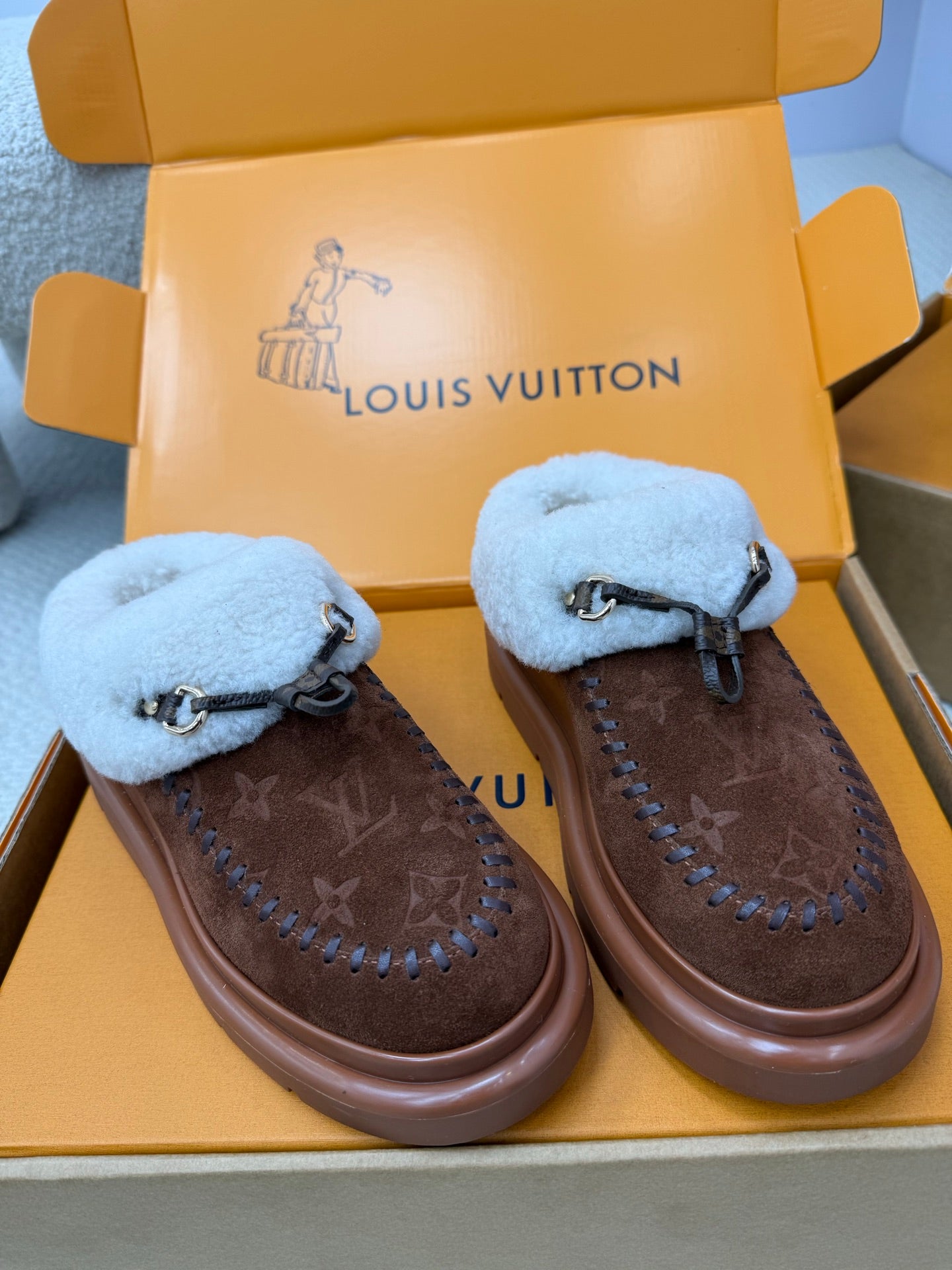 Louis Vuitton shearling mules, two shoes with brown monogram pattern and light blue cuffs
