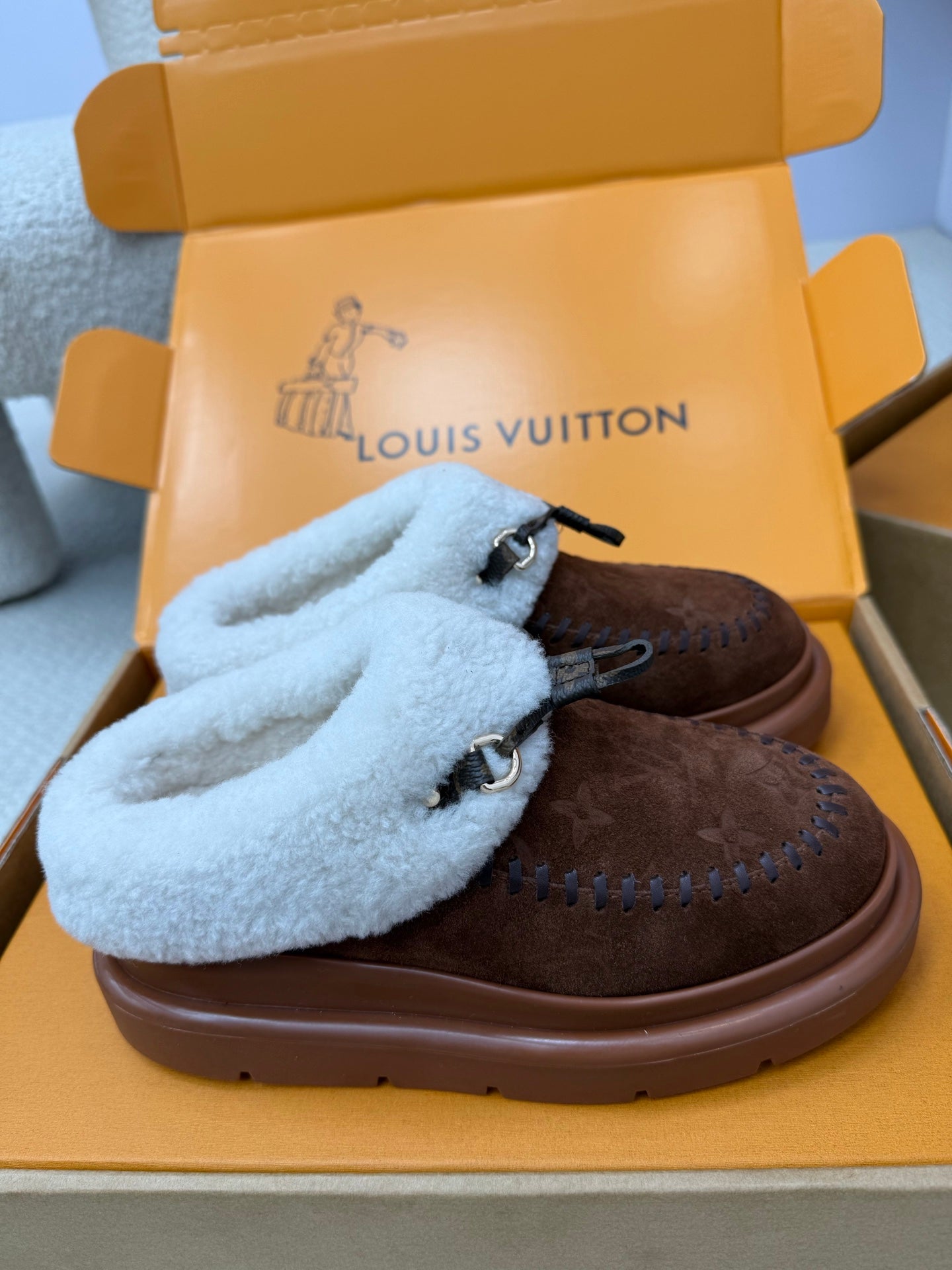Louis Vuitton shearling mules, close view of brown monogram upper with blue fuzzy strap