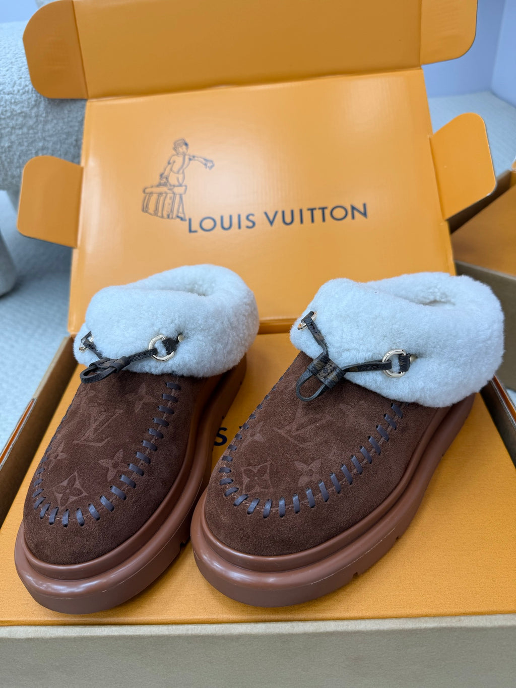 Louis Vuitton shearling mules, front view showing brown monogram uppers and blue fur cuffs