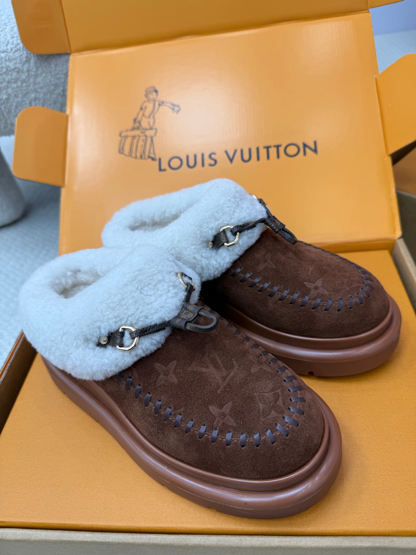 Louis Vuitton shearling mules, side view of brown monogram uppers and blue fur trim
