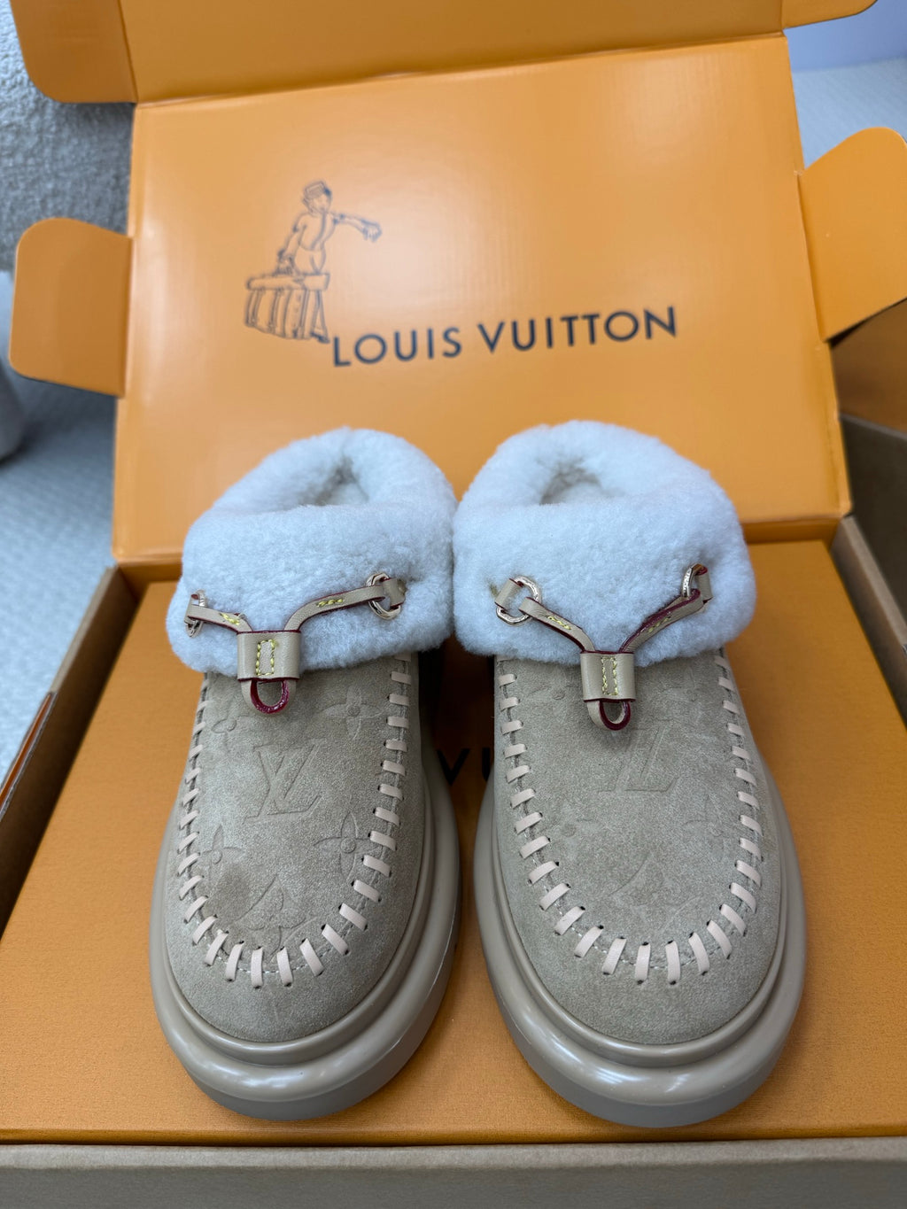 Pair of light blue shearling slip-on sneakers with grey suede uppers and side stitching