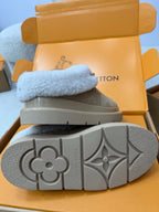 Bottom view of grey slip-on sneakers with patterned rubber outsole and signature logo