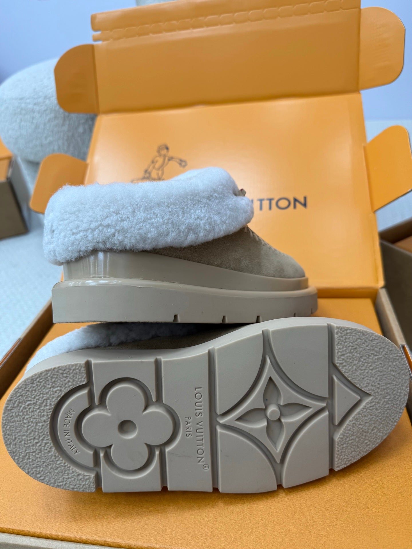 Bottom view of grey slip-on sneakers with patterned rubber outsole and signature logo