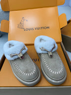 Grey suede slip-on sneakers with light blue fur straps and metal buckle accents