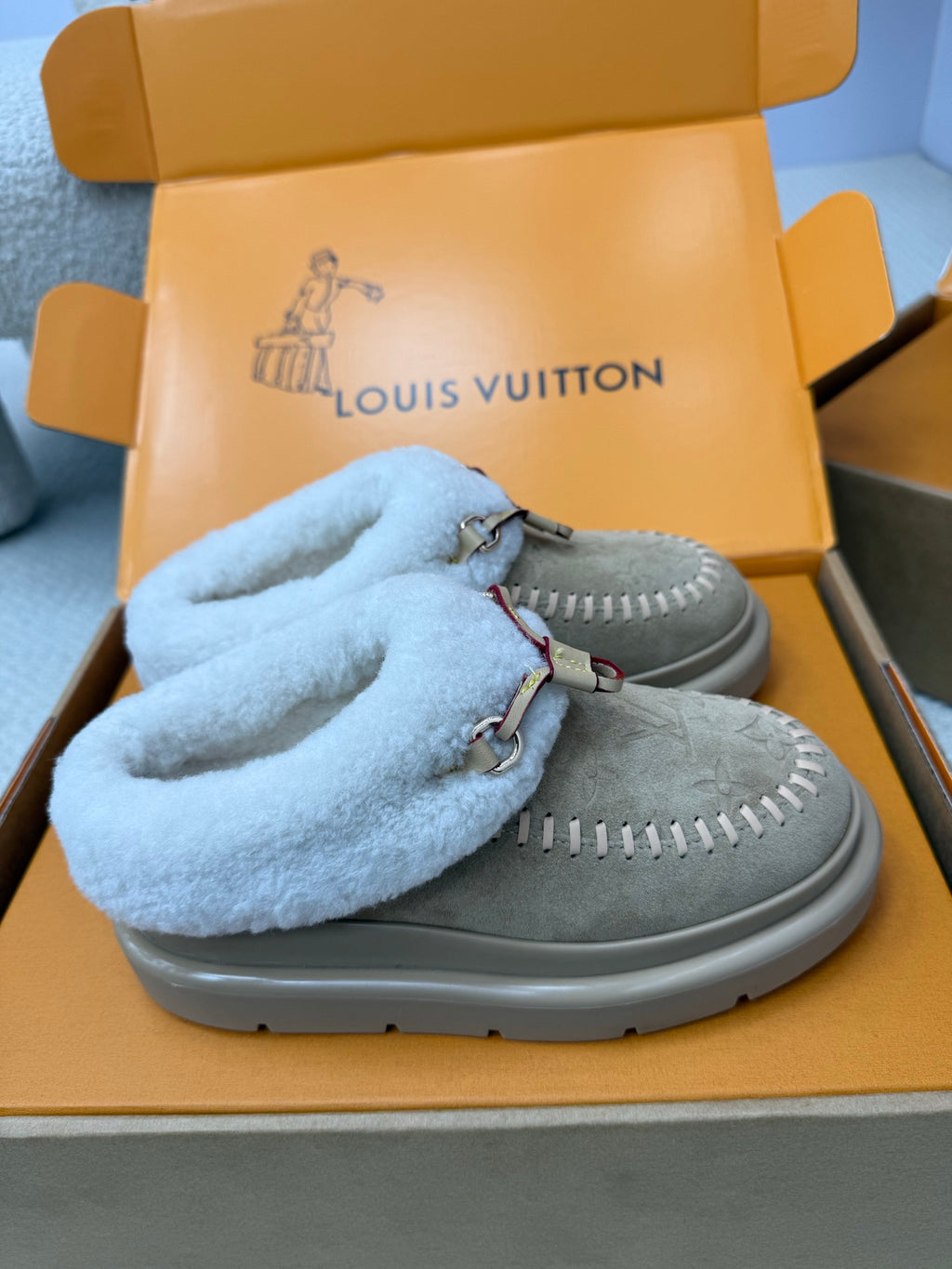 Light blue shearling slide sneakers over grey suede with stitched vamp and thick sole
