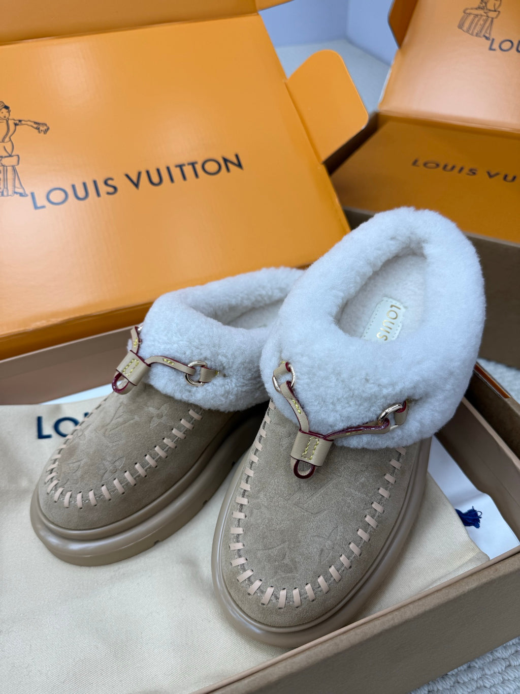 Grey suede slip-on sneakers with light blue fur uppers, buckle straps, and stitched edges