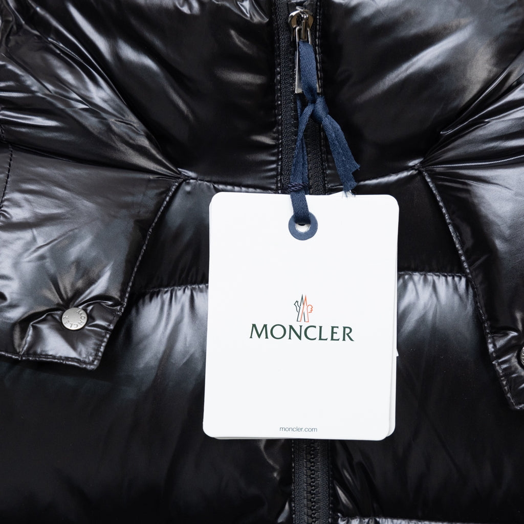 Moncler black puffer coat front with hanging tag, blue zipper pull and quilted rows