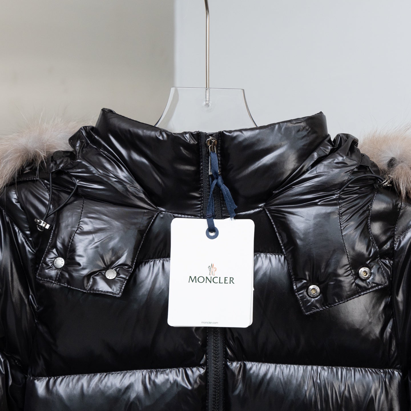 Moncler black puffer coat with fur hood, snap pockets, and hanging price tag