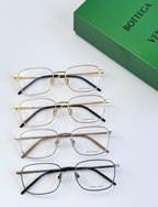 Set of four eyeglass frames with clear lenses in gold, silver, and dark tones