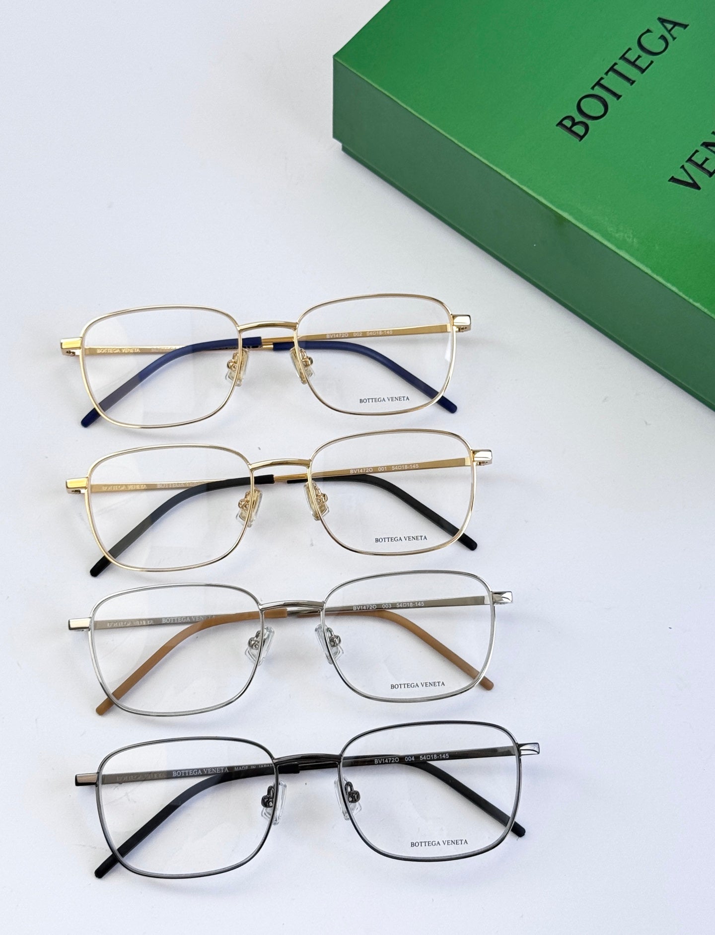 Set of four eyeglass frames with clear lenses in gold, silver, and dark tones