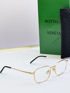 Gold eyeglass frames with clear lenses and black temple arms