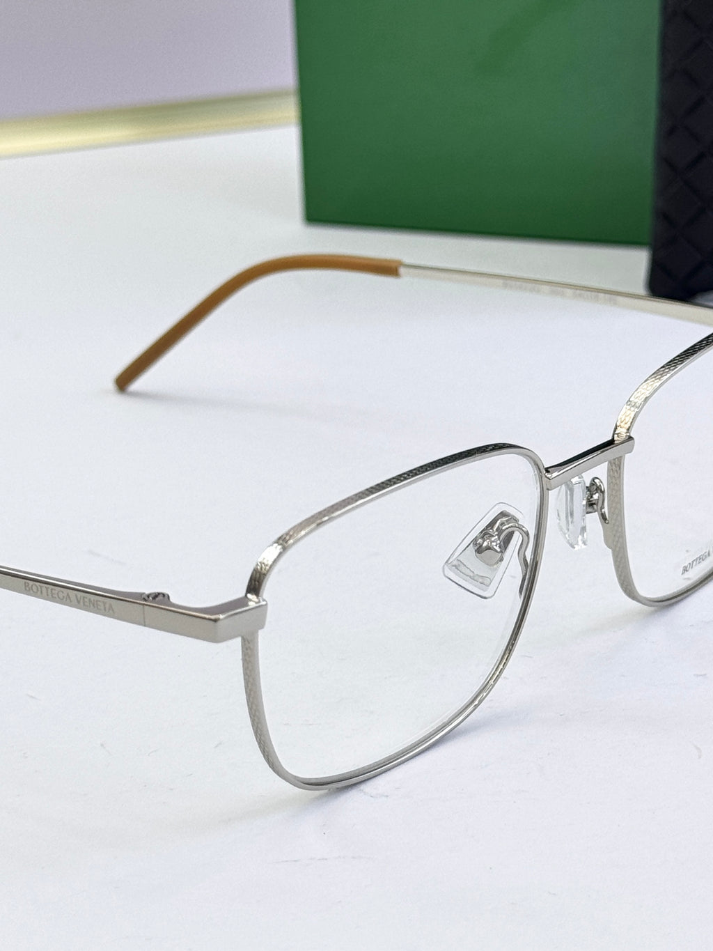 Silver eyeglass frames with clear lenses and light brown arms
