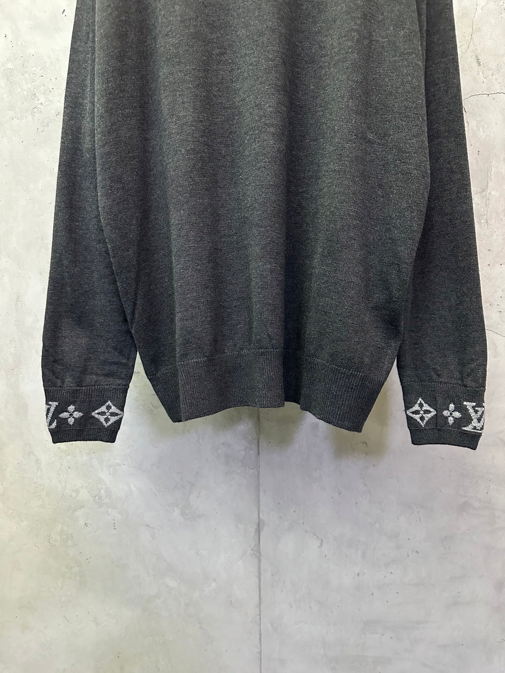 Dark gray sweater hem with ribbed cuffs and logo graphic knit trim