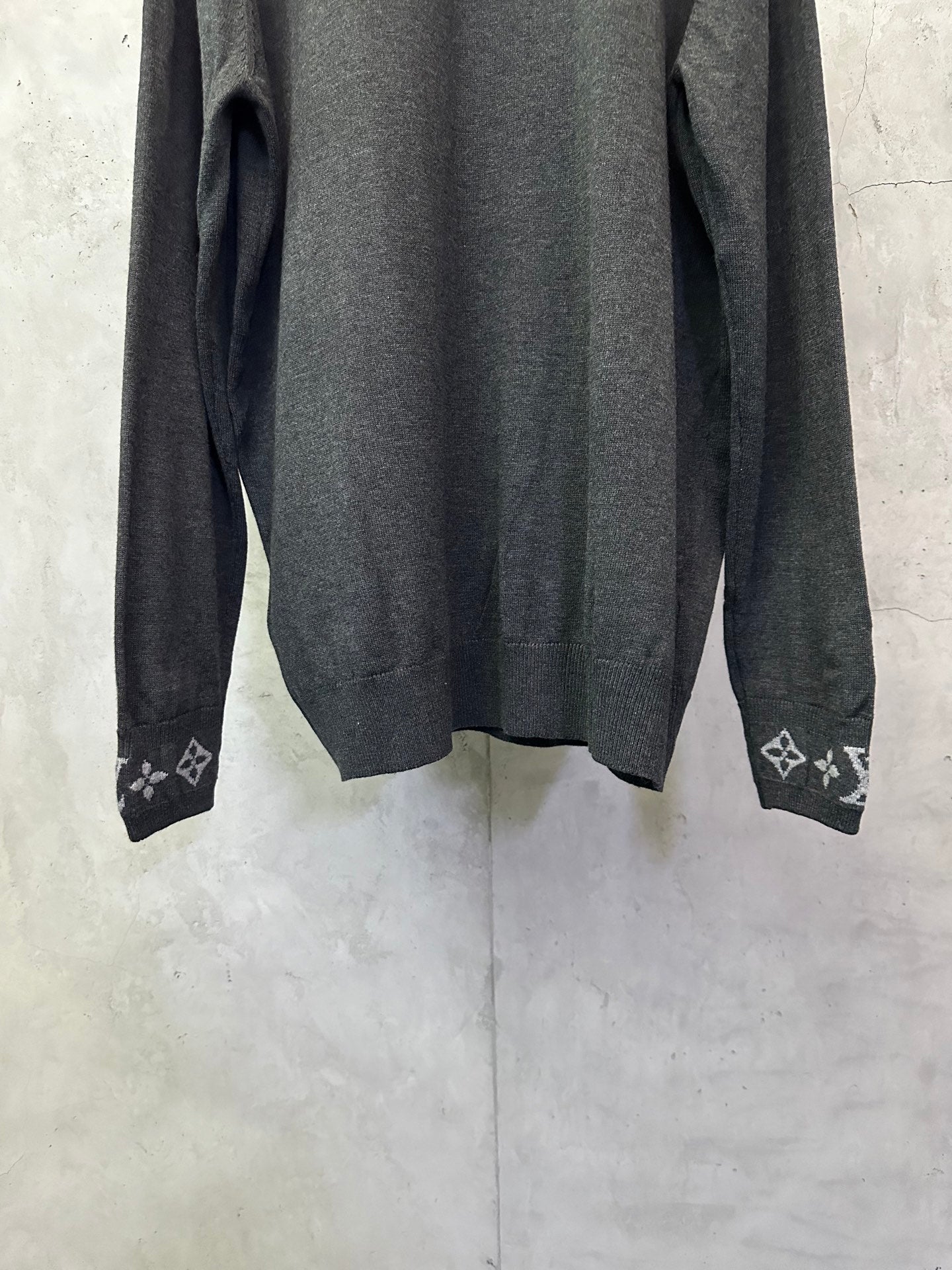 Dark gray long-sleeve sweater with ribbed cuffs and logo knit trim at hem