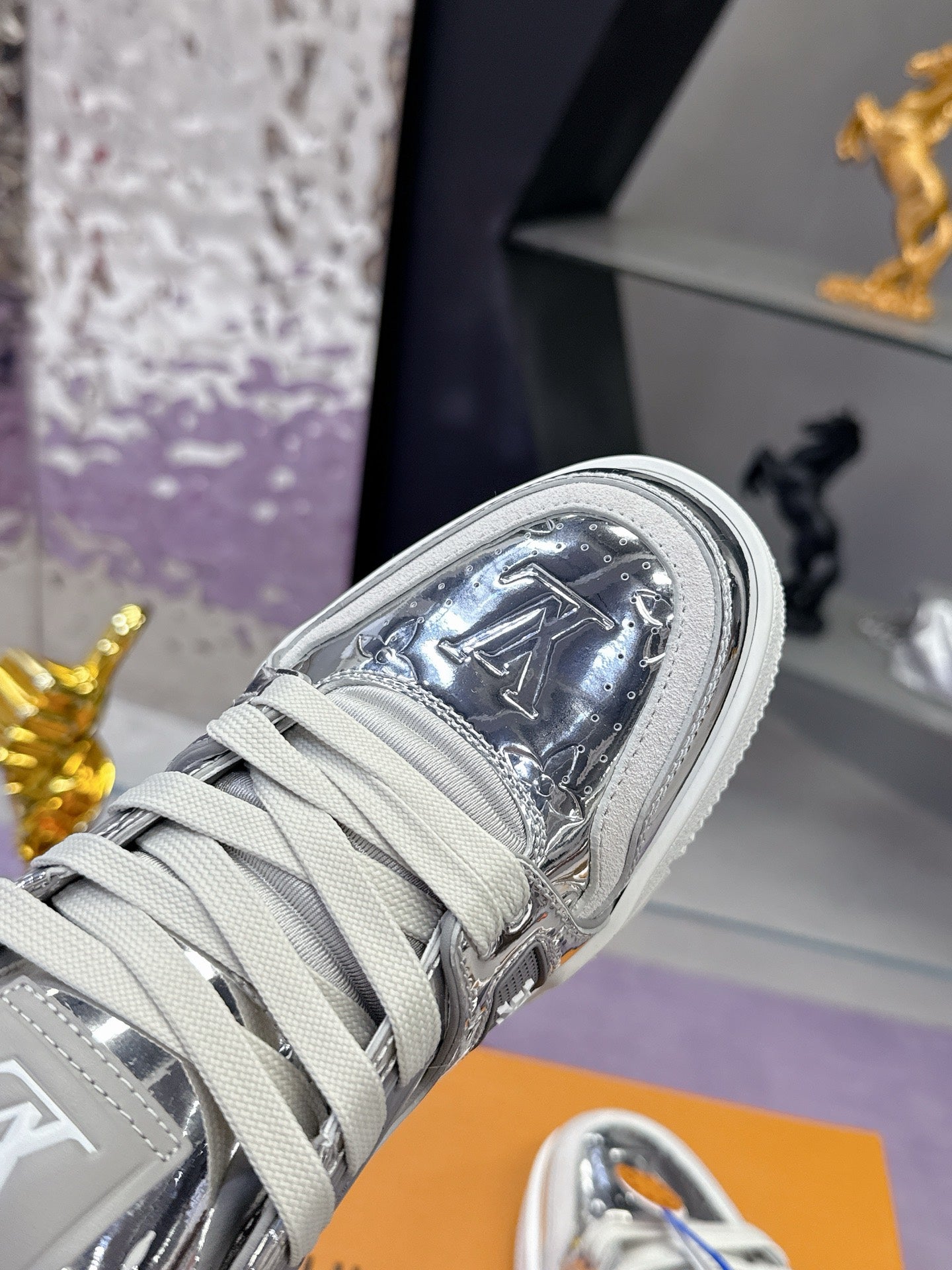 Louis Vuitton women's metallic silver sneaker close-up, laces and LV logo patch