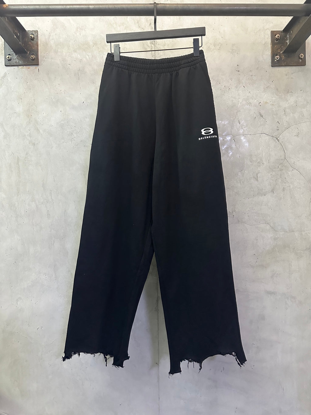 Balenciaga black wide-leg pants, elastic waist, frayed hem, small logo
