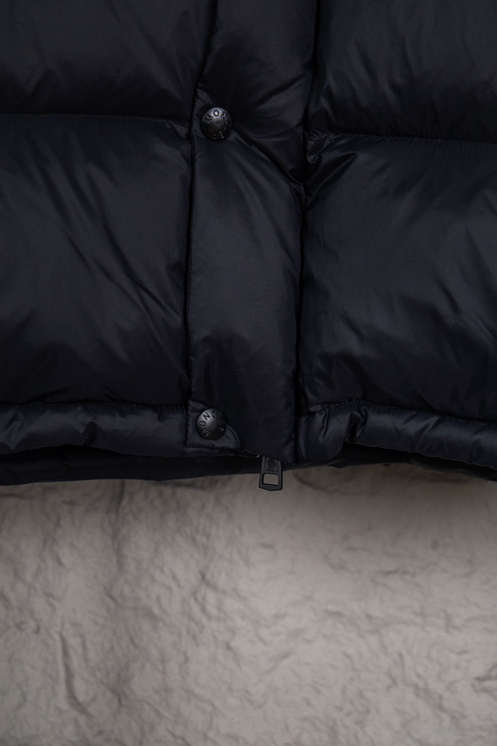 Moncler long puffer jacket front lower section with snap buttons and dark navy fabric