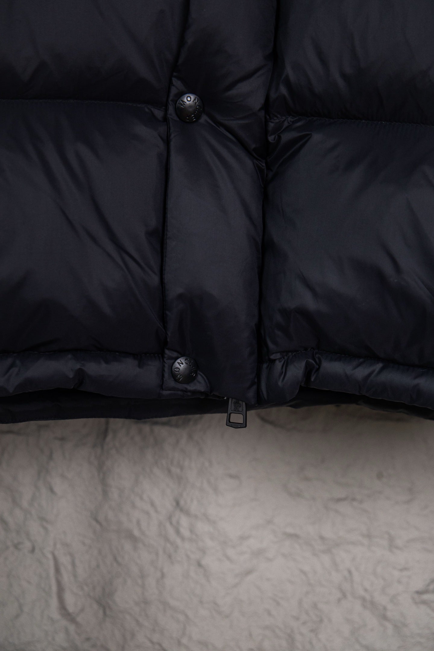 Moncler long puffer jacket front lower section with snap buttons and dark navy fabric