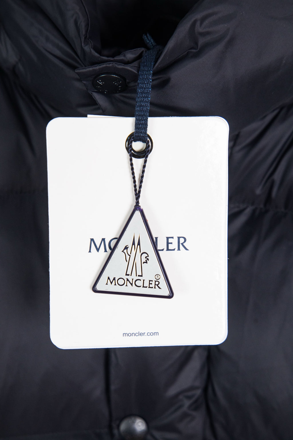 Moncler long puffer jacket with brand swing tag hanging from the hood opening