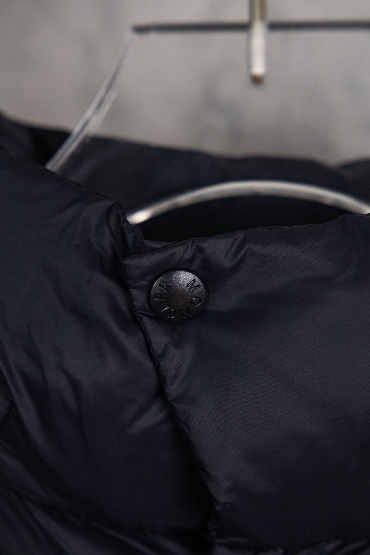 Moncler long puffer jacket neck area with embossed button and dark navy fabric