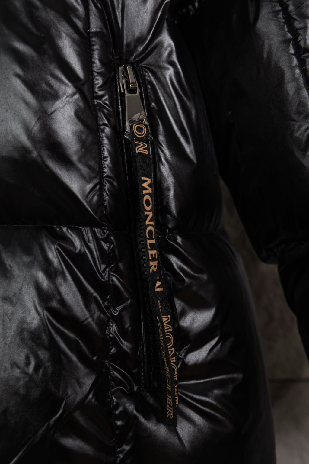 Moncler long puffer jacket zipper close-up, black with logo tape