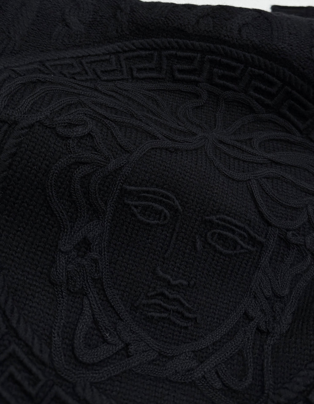 Versace black knit sweater front with large raised Medusa-style emblem pattern