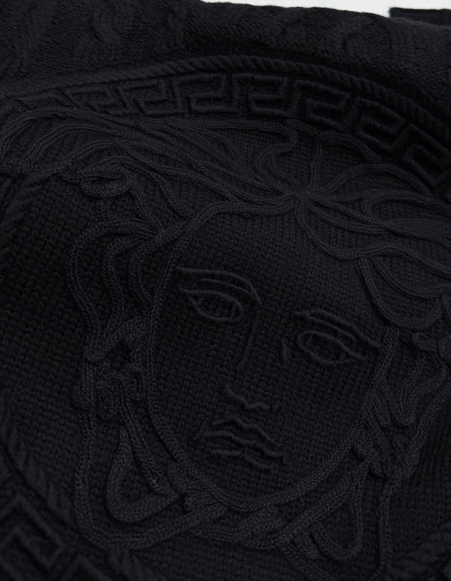 Versace black knit sweater front with large raised Medusa-style emblem pattern