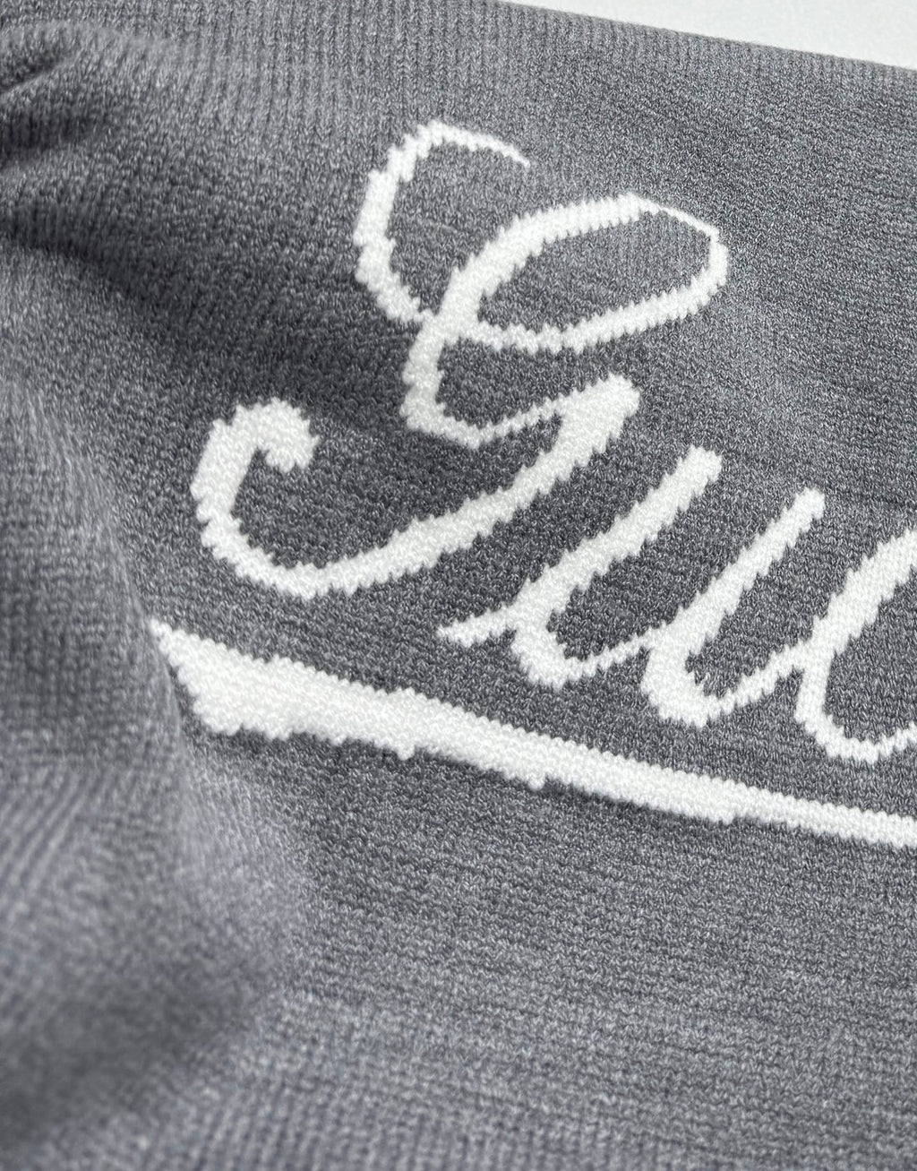 Gucci knit sweater front, white Gucci script logo on gray knit