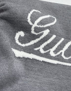 Gucci knit sweater front, white Gucci script logo on gray knit