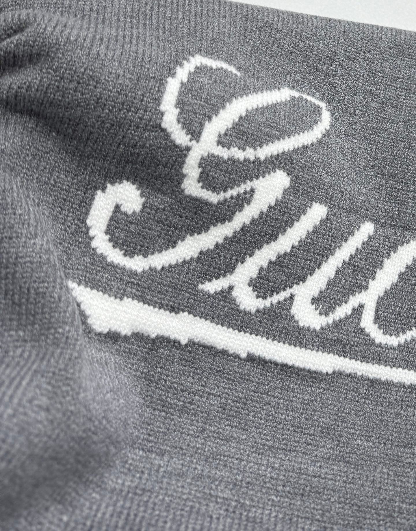 Gucci knit sweater front, white Gucci script logo on gray knit
