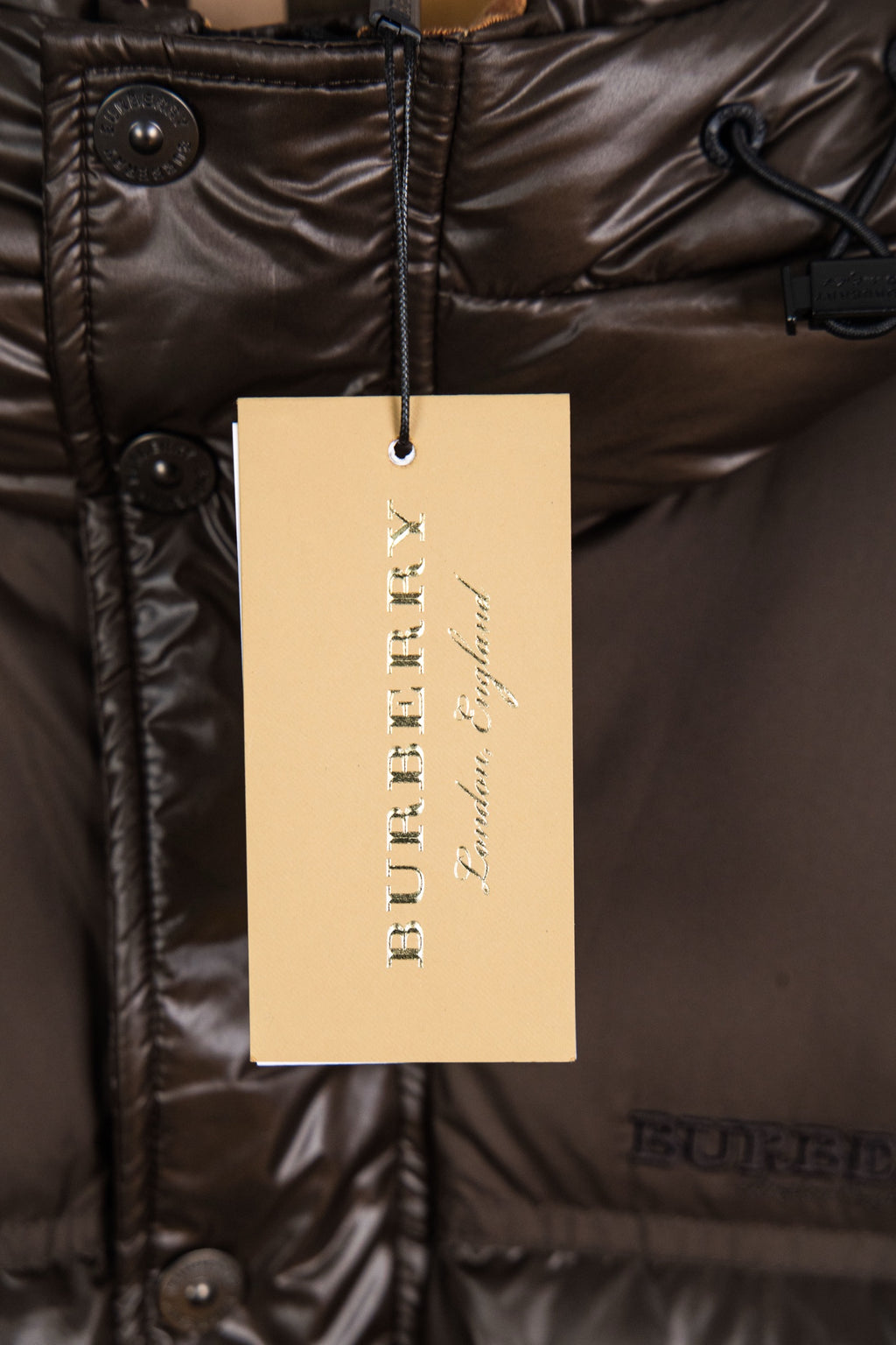 Long puffer jacket with visible care label on dark brown fabric