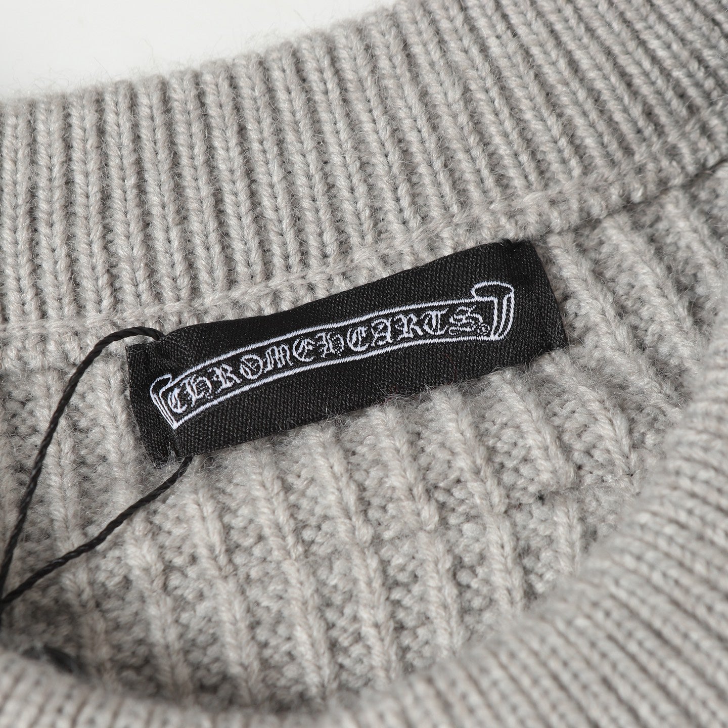 Light gray ribbed knit cardigan with woven brand label at the collar