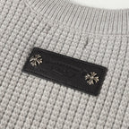 Light gray knit fabric with dark leather brand label and decorative studs