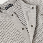 Light gray knit cardigan front with metal buttons and braided trim detail