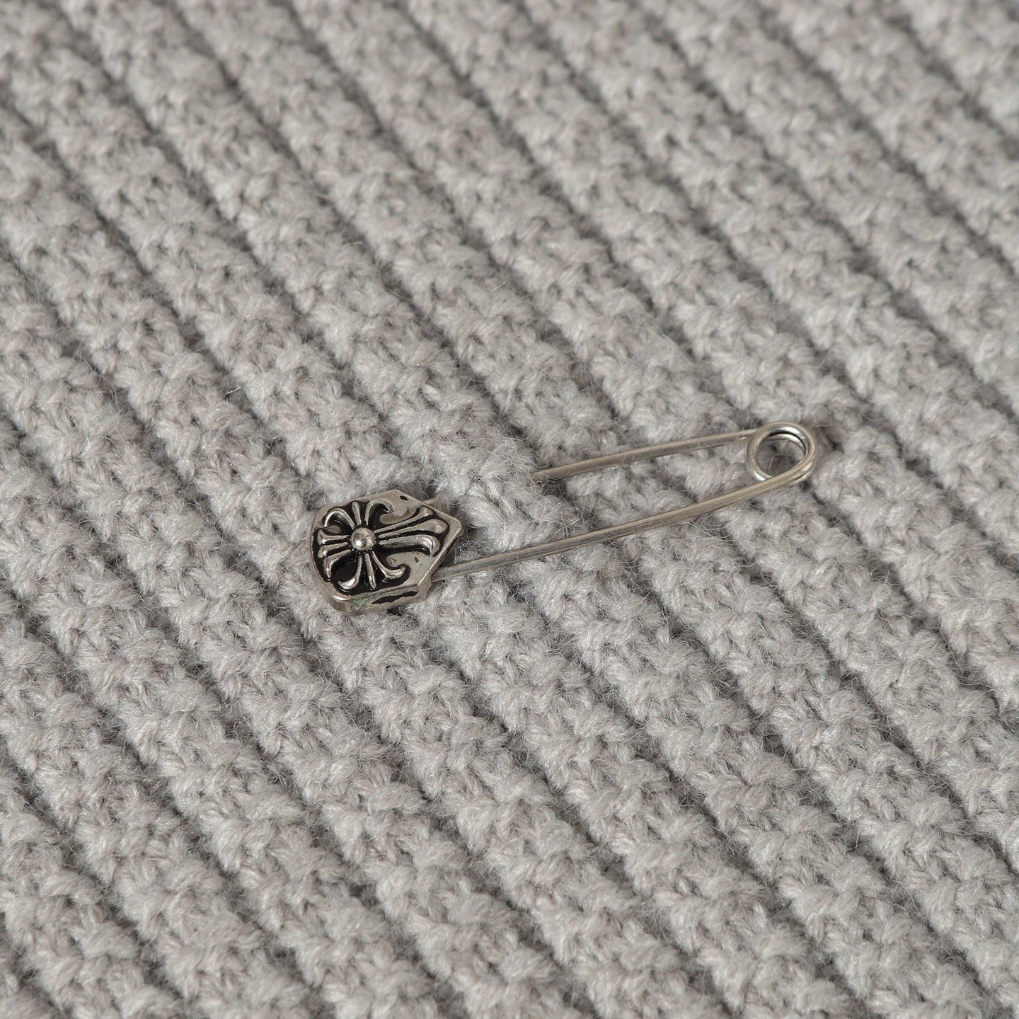 Light gray knit fabric with small metal pin ornament on ribbed texture