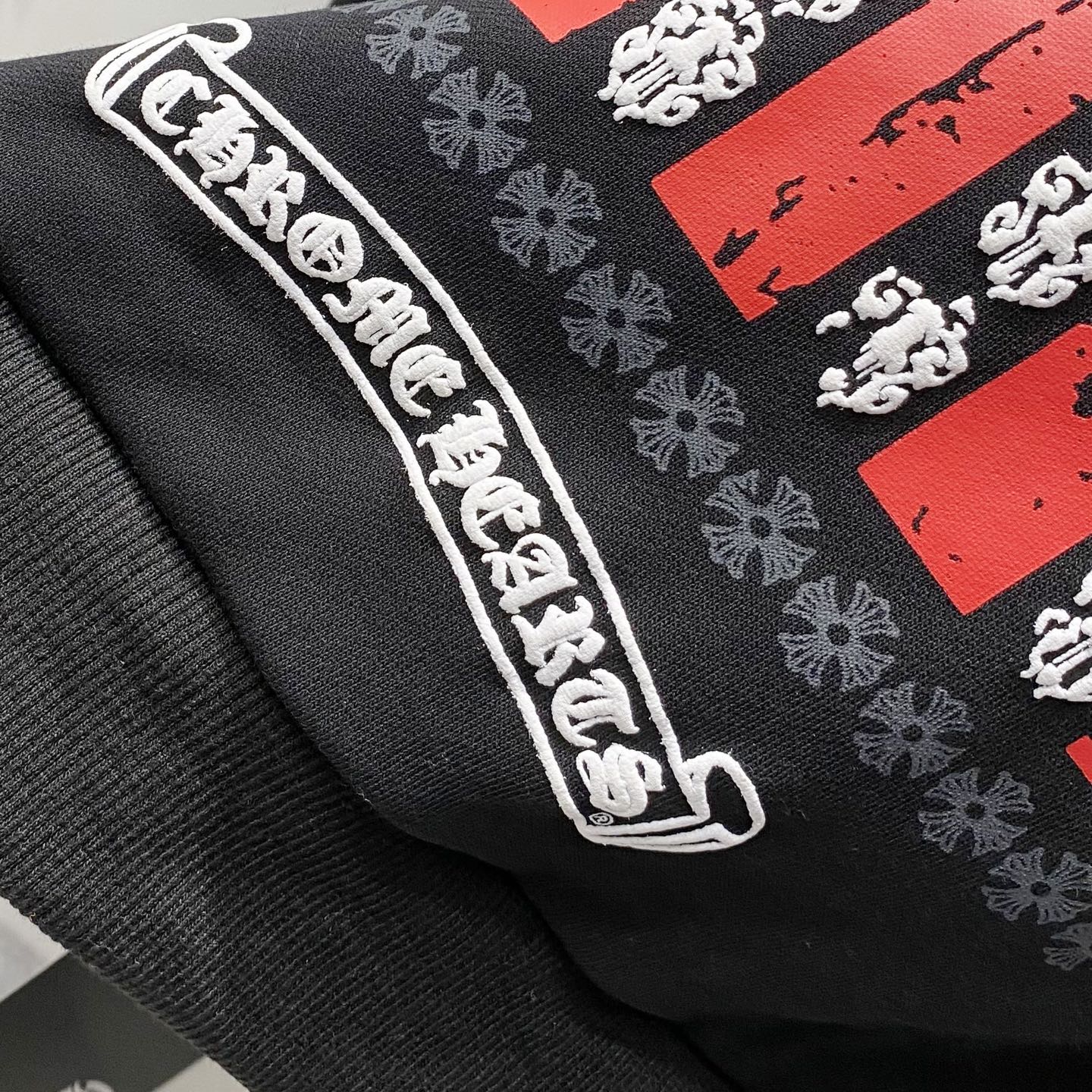 Dark hoodie sleeve with embroidered graphic patch and white logo trim