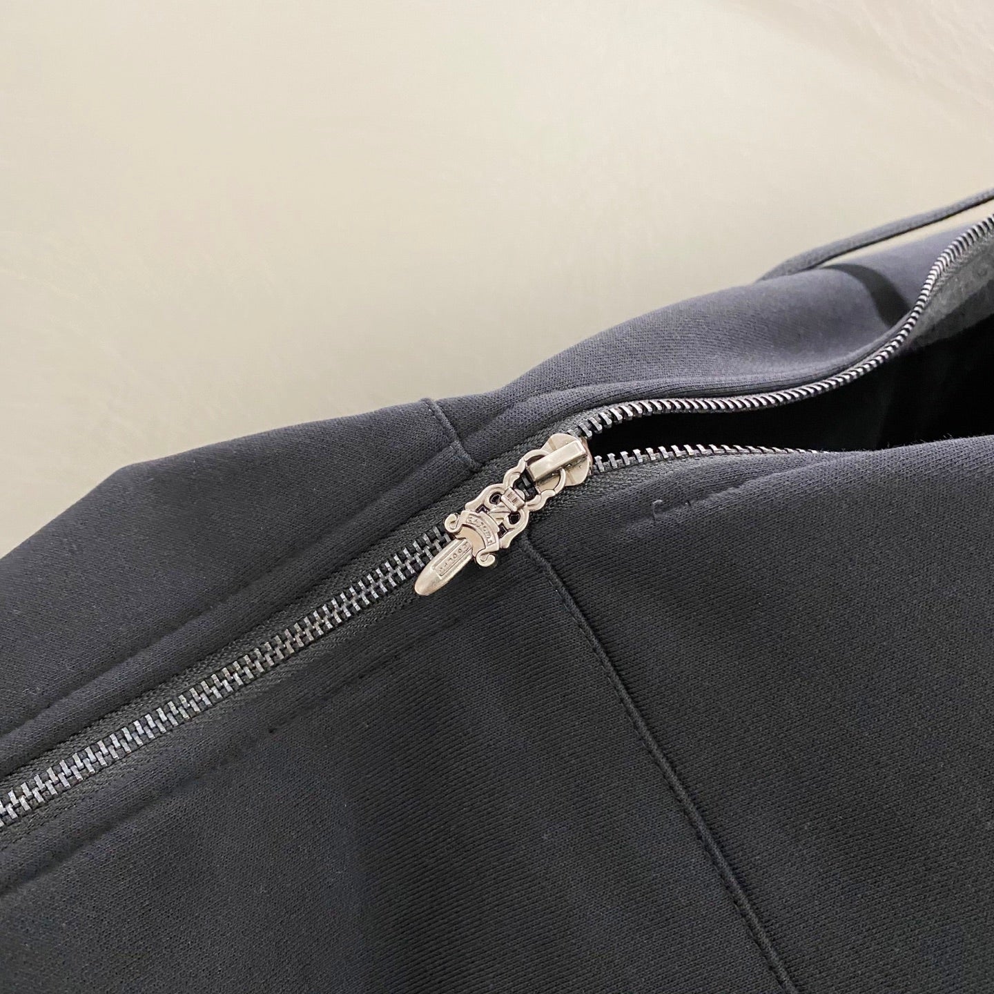 Dark hoodie zipper and metal pull detail on the front