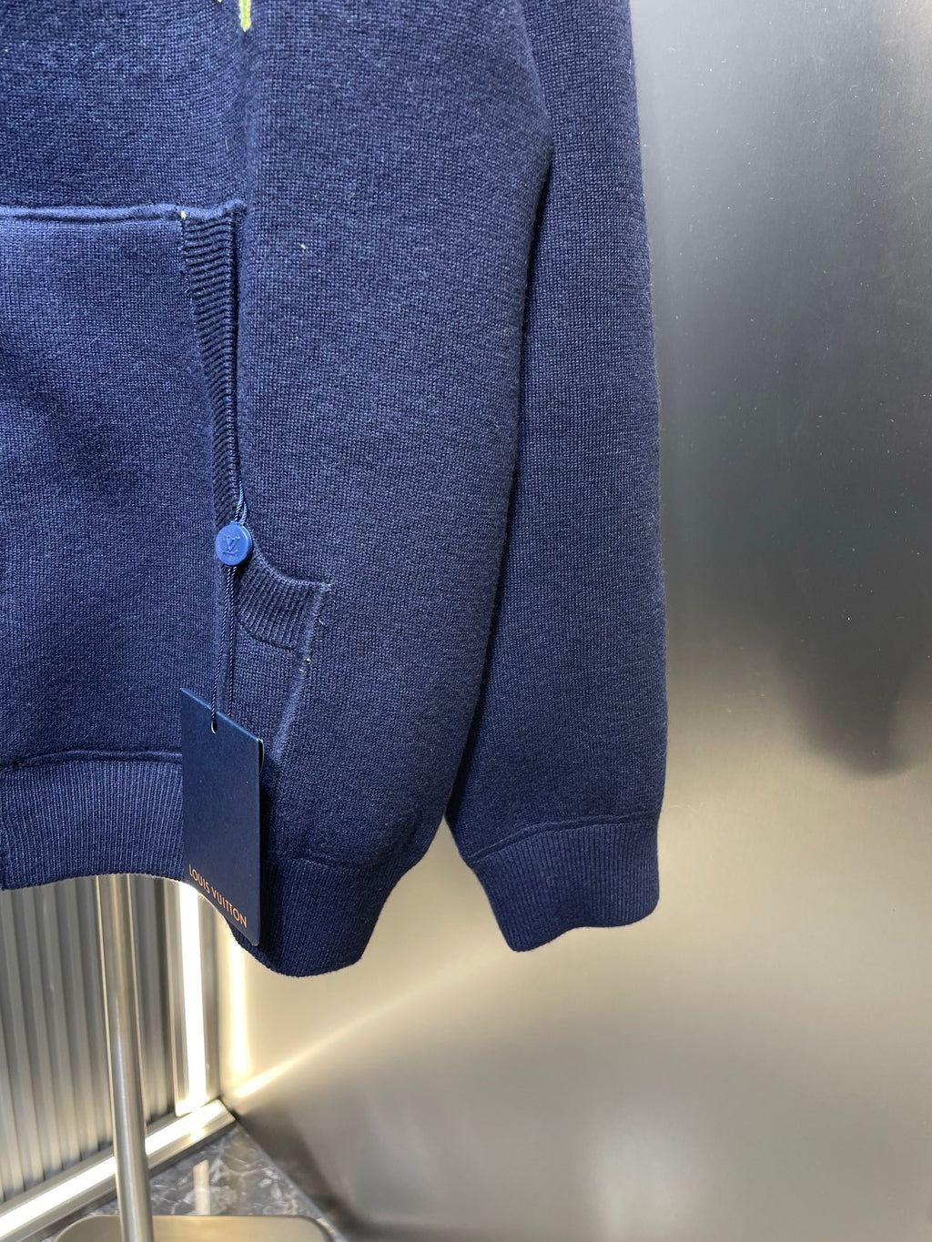 Navy zip-up hoodie hem with front pocket and elastic cuffs, partial zipper view.