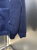 Navy zip-up hoodie hem with front pocket and elastic cuffs, partial zipper view.