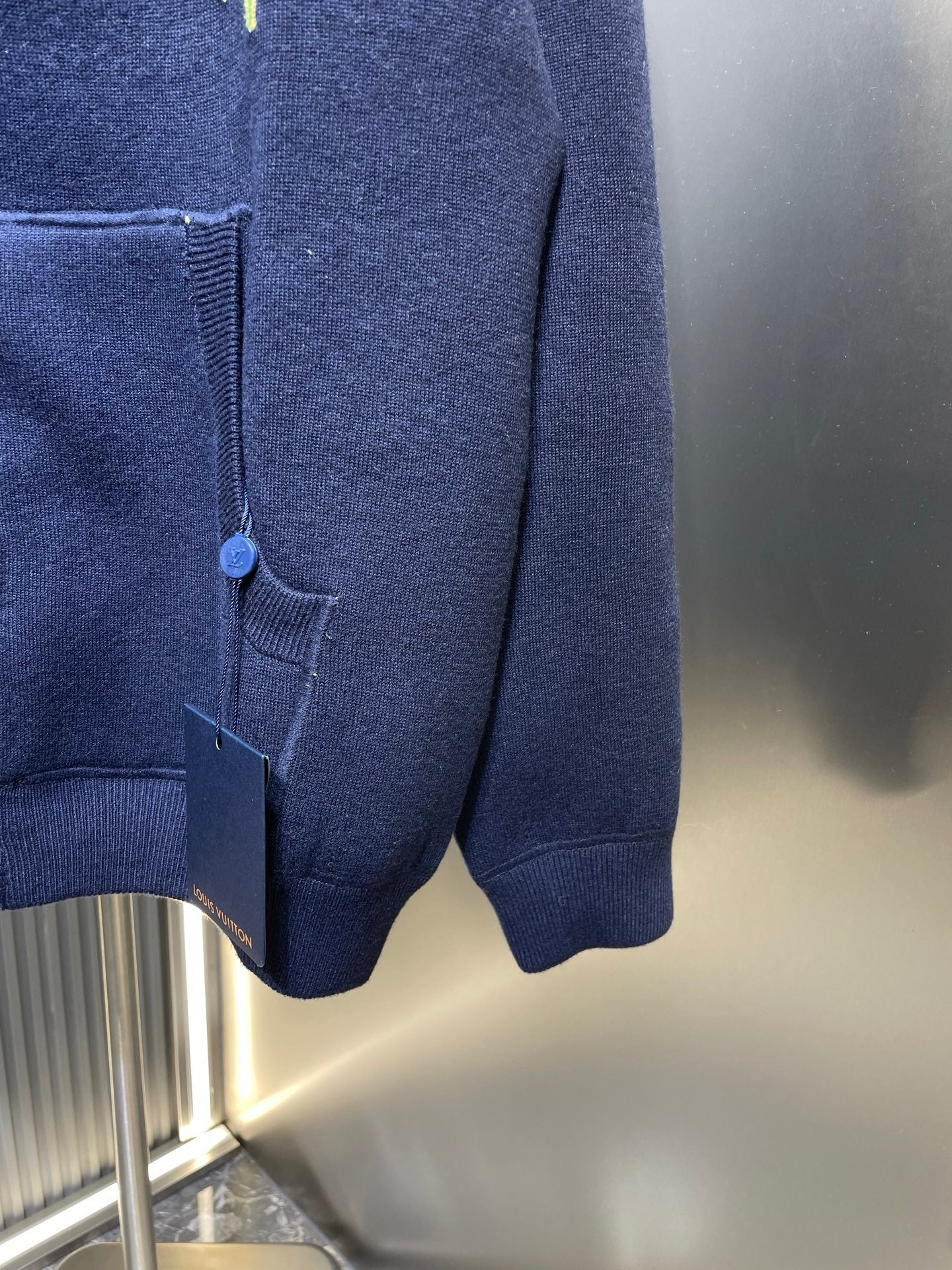 Navy zip-up hoodie hem with front pocket and elastic cuffs, partial zipper view.