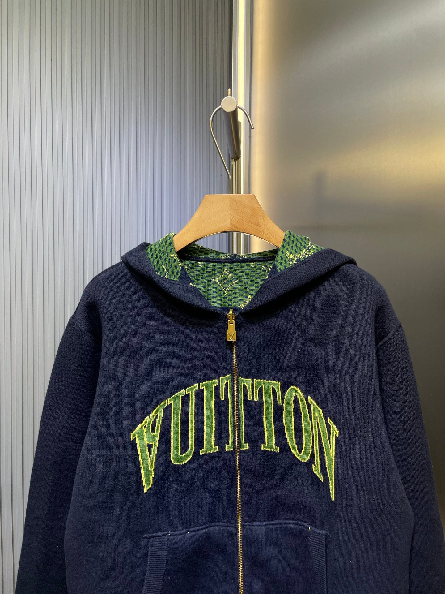 Navy Louis Vuitton zip-up hoodie with green logo print and patterned hood lining.