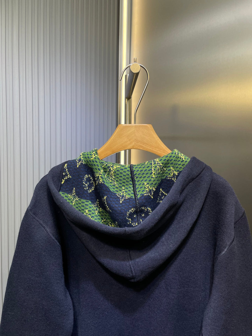 Navy zip-up hoodie with patterned green hood lining and drawstring detail.
