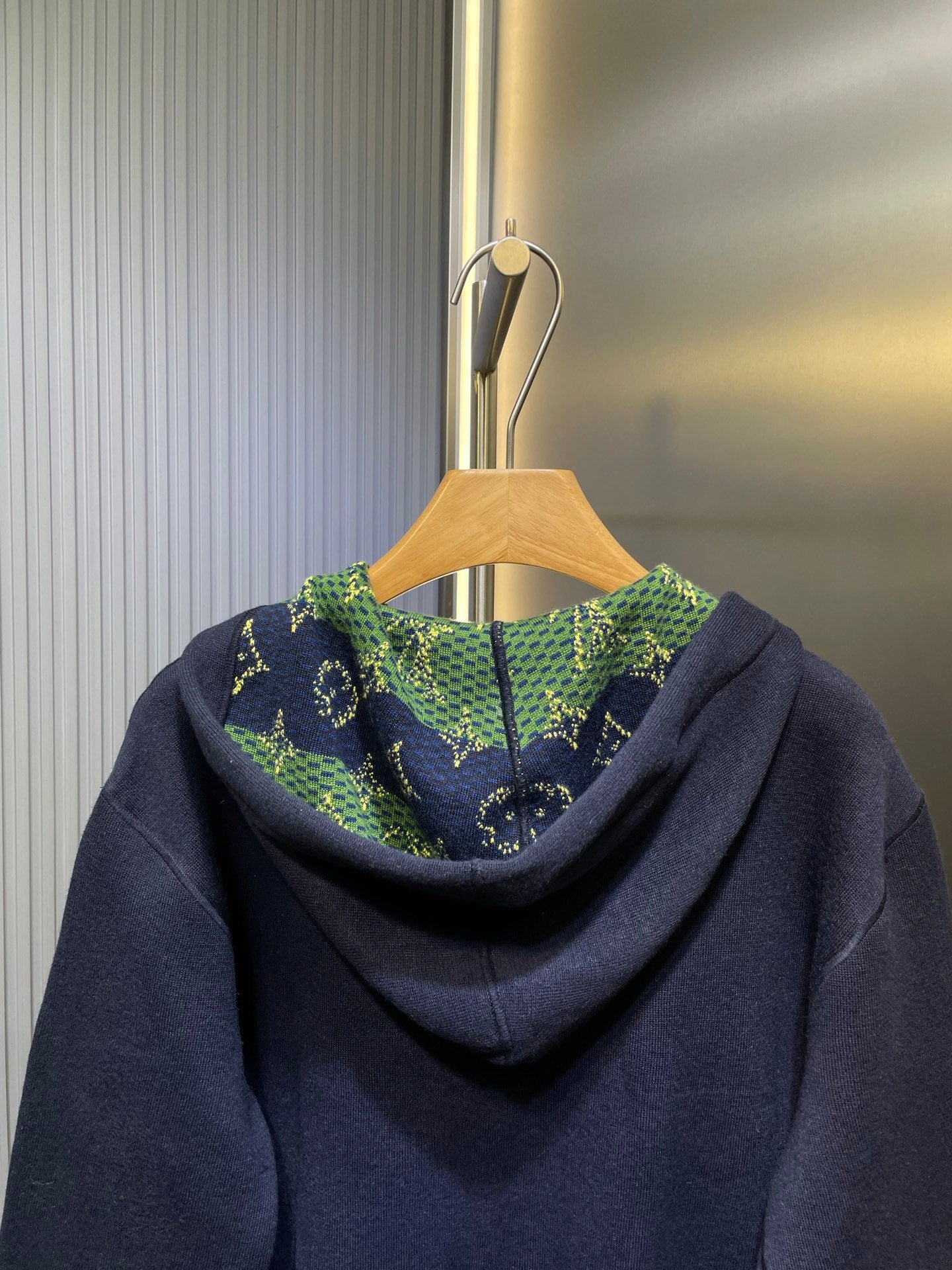 Navy zip-up hoodie with patterned green hood lining and drawstring detail.