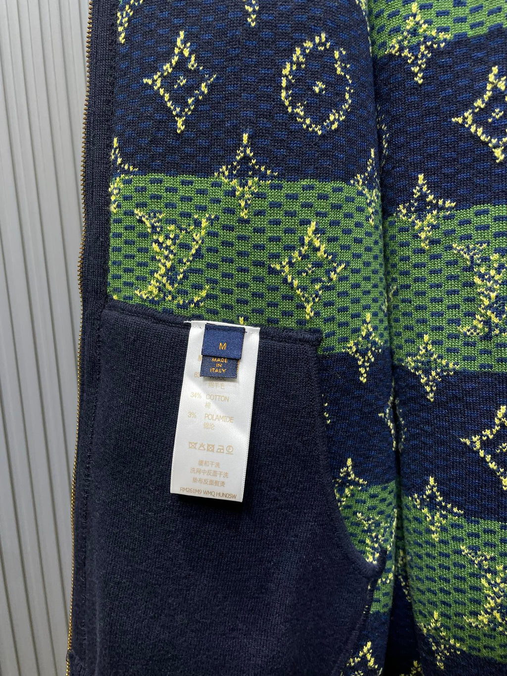 Close-up of navy hoodie fabric with green print and size tag labeled M.