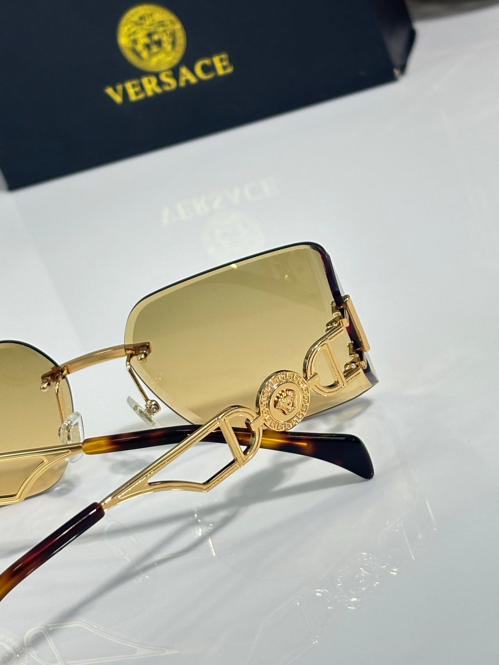 Versace sunglasses close-up of yellow lenses and ornate gold hinge detail